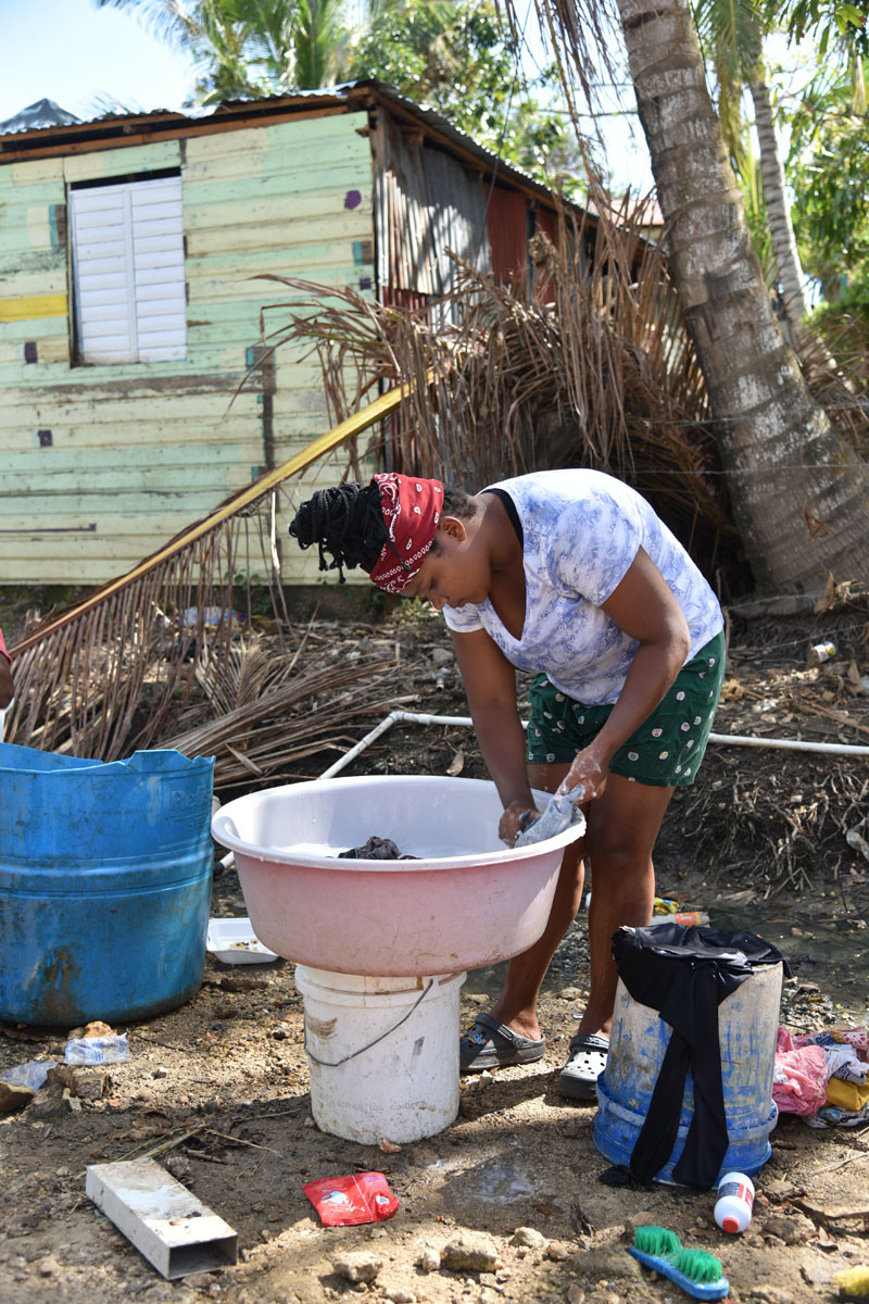 Esfuerzo. Carolina Cedeño lava algunas piezas de su casa afectadas por el ciclón.
