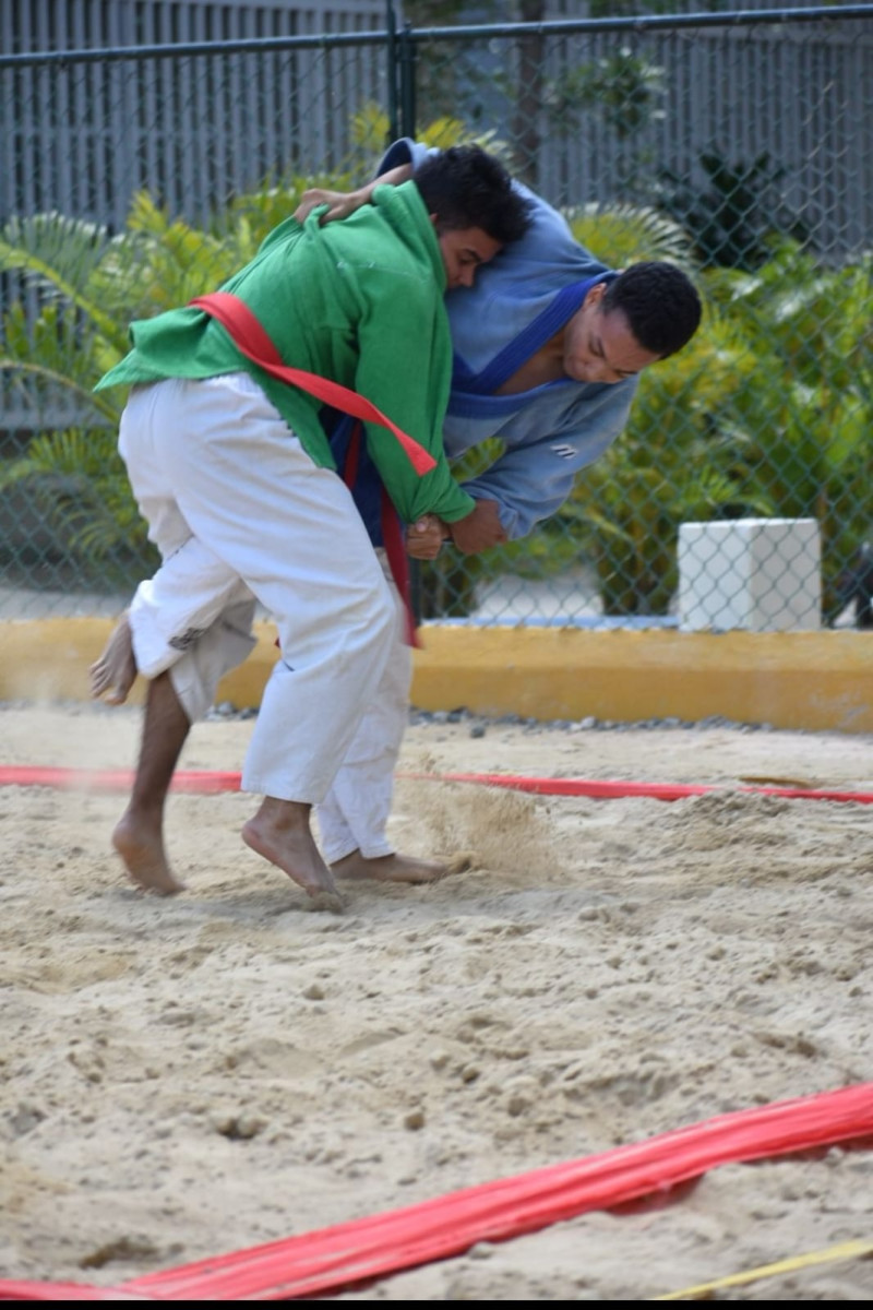 Peleadores en gran faena durante una pasada competencia de Kurash en la playa.