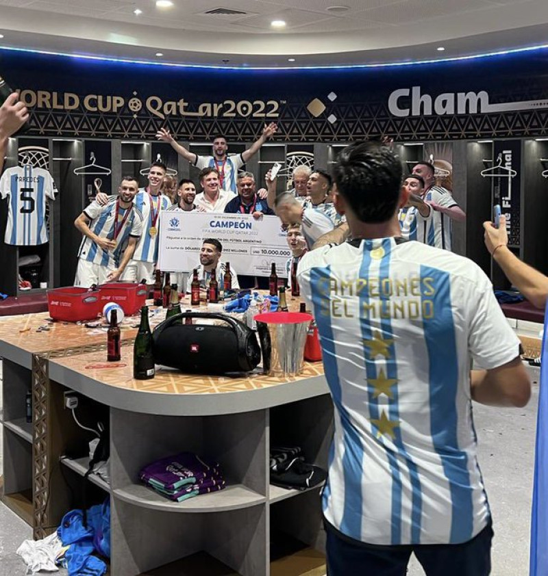 Lionel Messi y el presidente de la Conmbol, Alejandro Domínguez, sosteniendo el cheque de 10 millones de dolares por haber ganado la Copa Mundial 2022 en el vestuario junto a otros jugadores argentinos. Fuente: Twitter.
