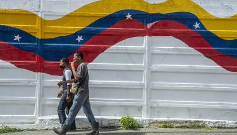 Dos personas pasan ante un mural con la bandera de Venezuela en Caracas. EUROPA PRESS