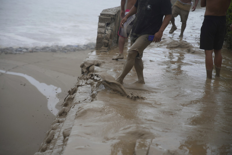 La gente patea lodo frente a un muro que cayó en la playa Punta Hermosa, provocado por las fuertes lluvias del ciclón Yaku en Lima, Perú, el miércoles 15 de marzo de 2023.