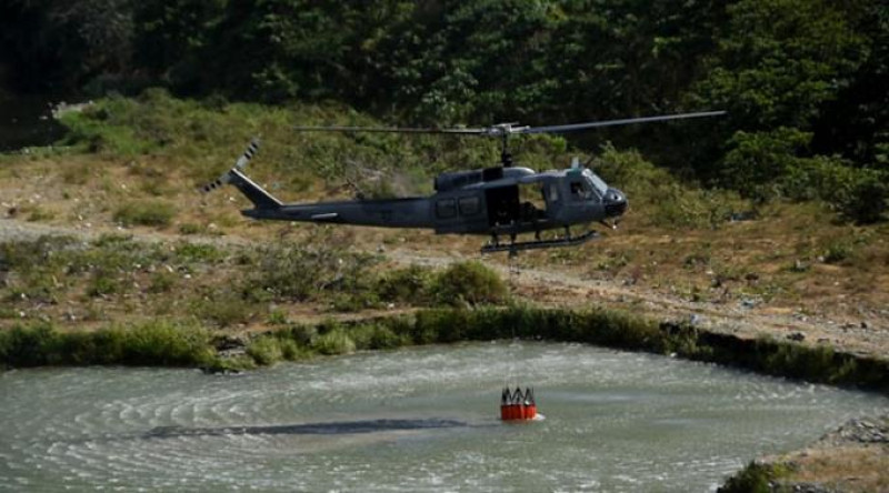 Un helicóptero de la Fuerza Aérea desciende en un río para tomar agua en un balde, para ser utilizada en la extinción de un incendio.