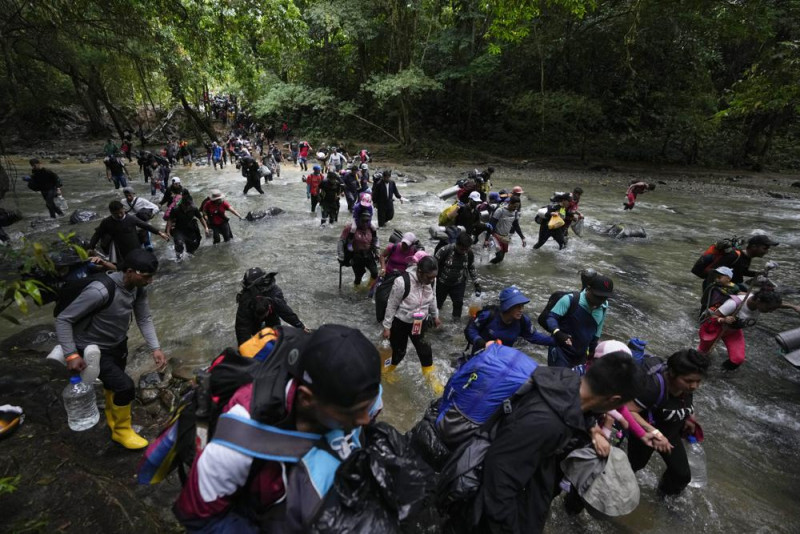 Migrantes, en su mayoría venezolanos, cruzan un río en la selva del Darién el 15 de octubre de 2022, en un recorrido de Colombia a Panamá, con la esperanza de seguir luego su viaje hacia Estados Unidos. La Agencia de la ONU para los Refugiados (ACNUR) y la Organización Internacional para las Migraciones (OIM) indicaron en un comunicado el jueves 13 de abril de 2023 que más 100.000 migrantes cruzaron esa ruta en los primeros meses del año y que, de seguir la tendencia, la cifra a final del año podría superar los 400.000. (AP Foto/Fernando Vergara, Archivo)