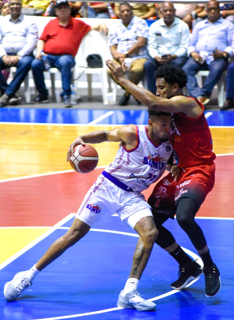 Jeromy Rodríguez, de Sameji, maneja el balón ante la defensa de Juan Guerrero, de Plaza Valerio, en acción del primer partido de la serie final del baloncesto de Santiago.