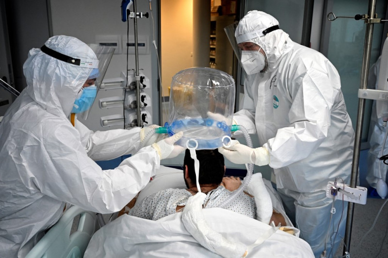 Médicos ayudan a un paciente a colocarse una nueva tecnología que reduce la necesidad de intubación por Covid-19.