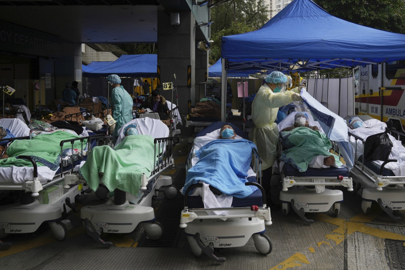 Los pacientes yacen en camas de hospital mientras esperan en un área de tratamiento temporal improvisada fuera del Centro Médico Caritas en Hong Kong, el viernes 18 de febrero de 2022. La Organización Mundial de la Salud rebajó su evaluación de la pandemia de coronavirus el viernes 5 de mayo de 2023 , diciendo que ya no califica como una emergencia global. (Foto AP/Kin Cheung, archivo)