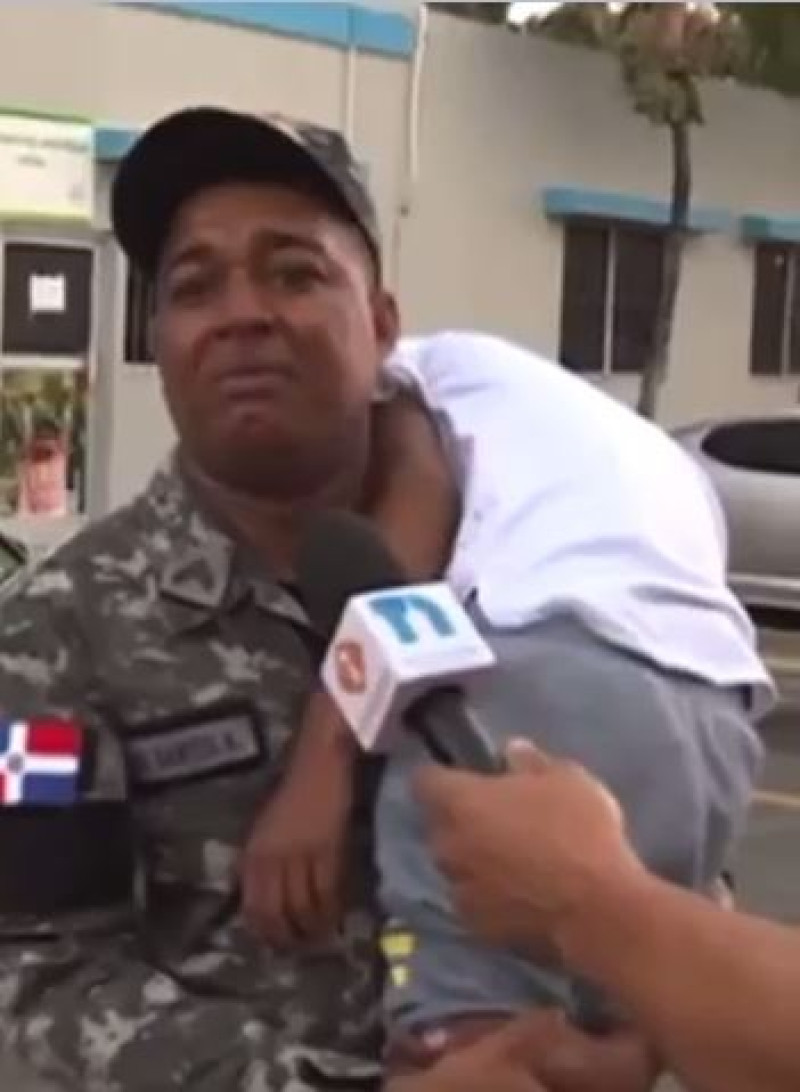 Agente de la Policía Nacional mientras sostiene a su hijo en brazos.
