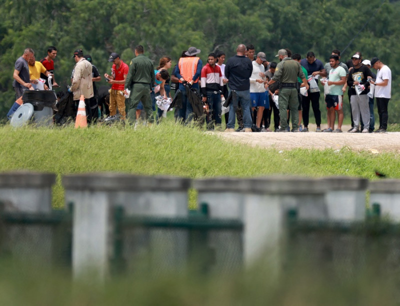 Migrantes caminan hacia donde la Patrulla Fronteriza de los Estados Unidos los procesa después de que cruzaron a los Estados Unidos desde México