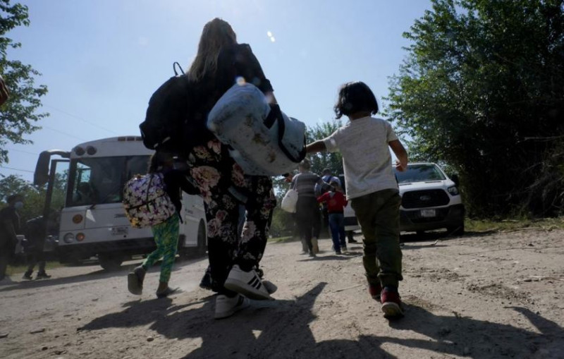 Una familia de migrantes venezolanos se dirige hacia un autobús de la Patrulla Fronteriza después de que cruzaran con otras personas de México hacia Estados Unidos