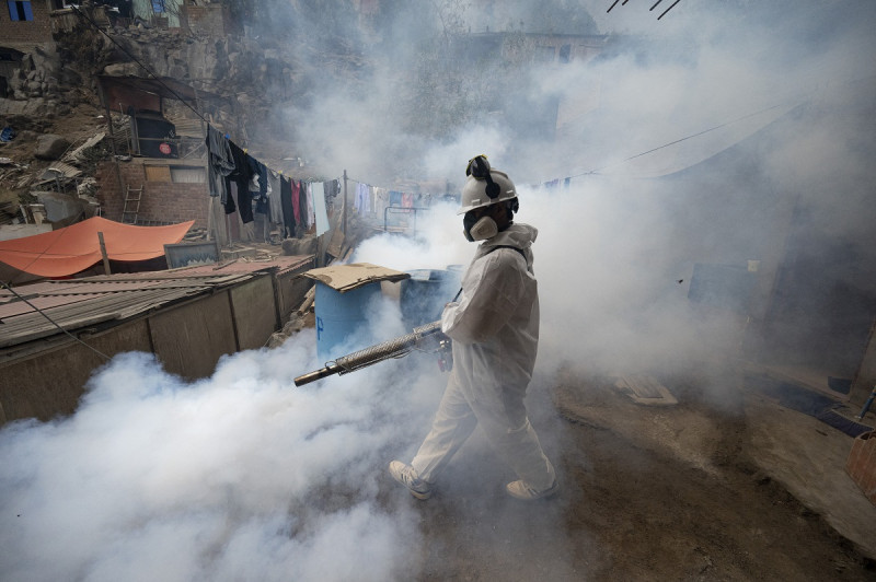 Un miembro de una brigada de salud fumiga una calle contra el virus del dengue en un barrio de chabolas en las colinas del distrito de San Juan de Lurigancho, Lima, el 11 de mayo de 2023.