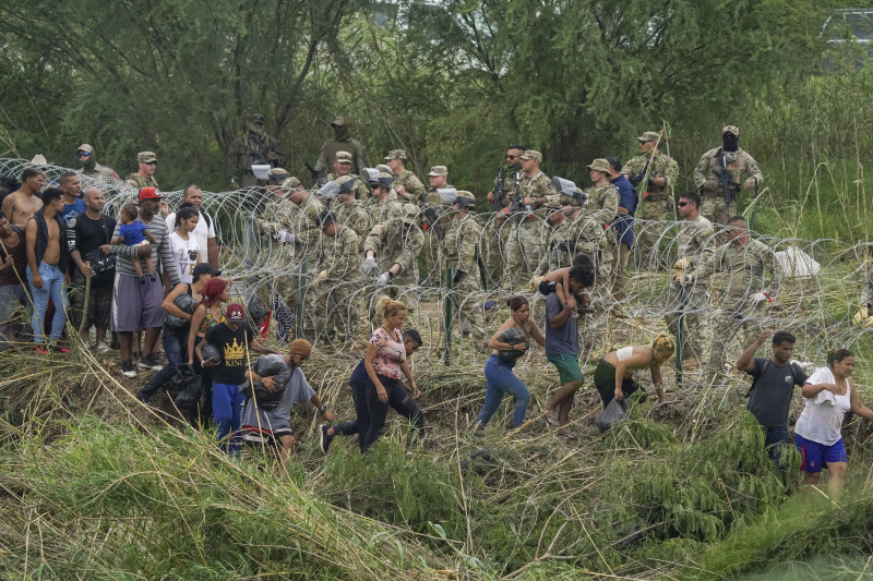 Los miembros de la Guardia Nacional de Texas refuerzan un tramo de alambre de púas mientras los migrantes intentan cruzar a los EE. UU.