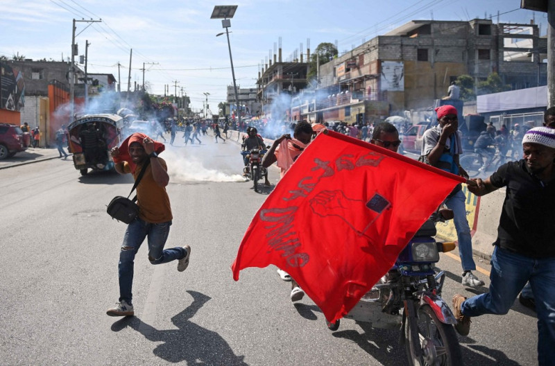 Trabajadores huyen de los gases lacrimógenos disparados por la policía mientras se manifiestan para exigir mejores salarios y condiciones de trabajo en Puerto Príncipe el 9 de mayo de 2023