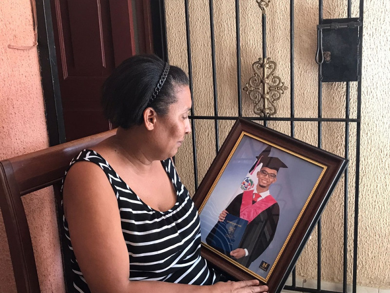 Berlinda sostiene el retrato de Joshua cuando se graduó de bachiller