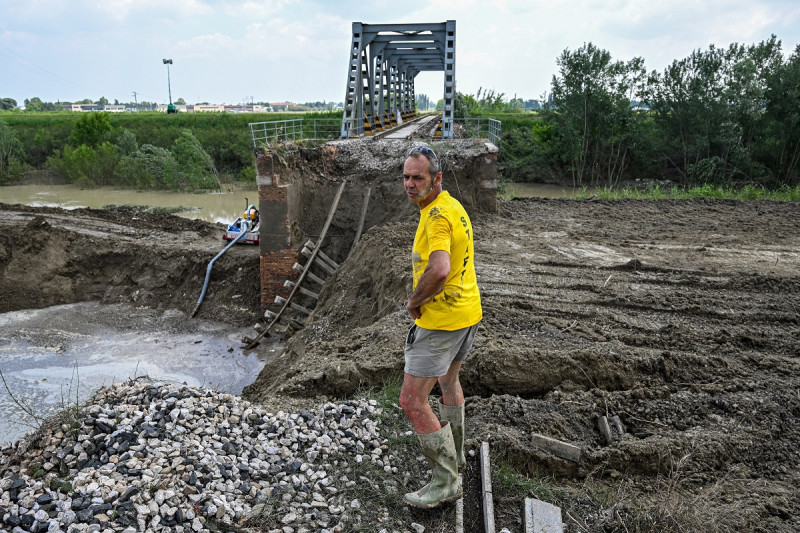 Una foto tomada el 21 de mayo de 2023 en Sant'Agata sul Santerno, cerca de Rávena, muestra a un trabajador de pie junto a un puente ferroviario derrumbado después de que las inundaciones mortales.