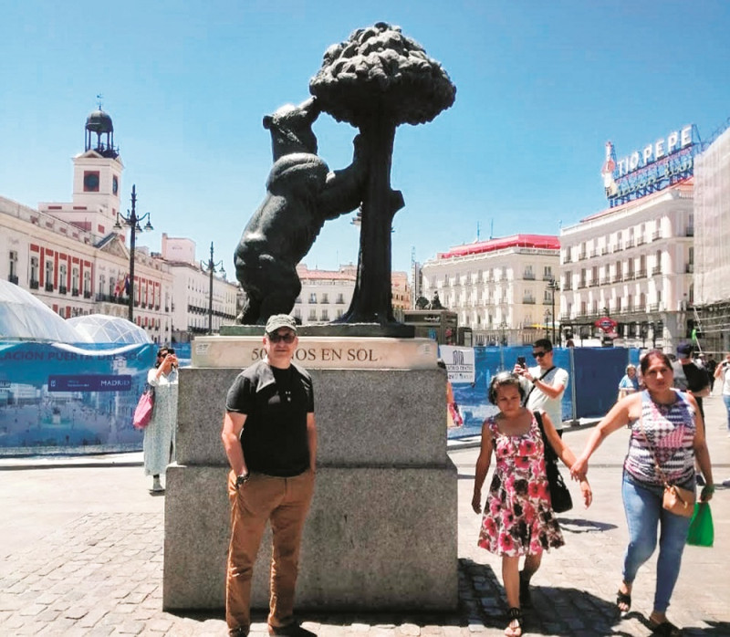 En la Puerta del Sol, Alexis se retrata delante de la escultura del Oso y el Madroño. Del lado izquierdo puede verse la torre del antiguo Real Edificio de Correos.