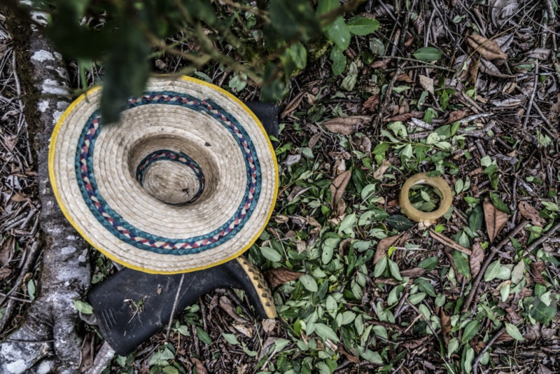 Las hojas de coca se muestran junto a un sombrero y un par de botas de goma en un campo de coca en un municipio del departamento de Nariño, Colombia