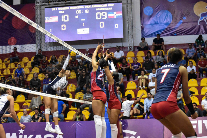 Chloe Chicole, de Estados Unidos, logra un potente remate ante la defensa de dos jugadoras de la República Dominicana.