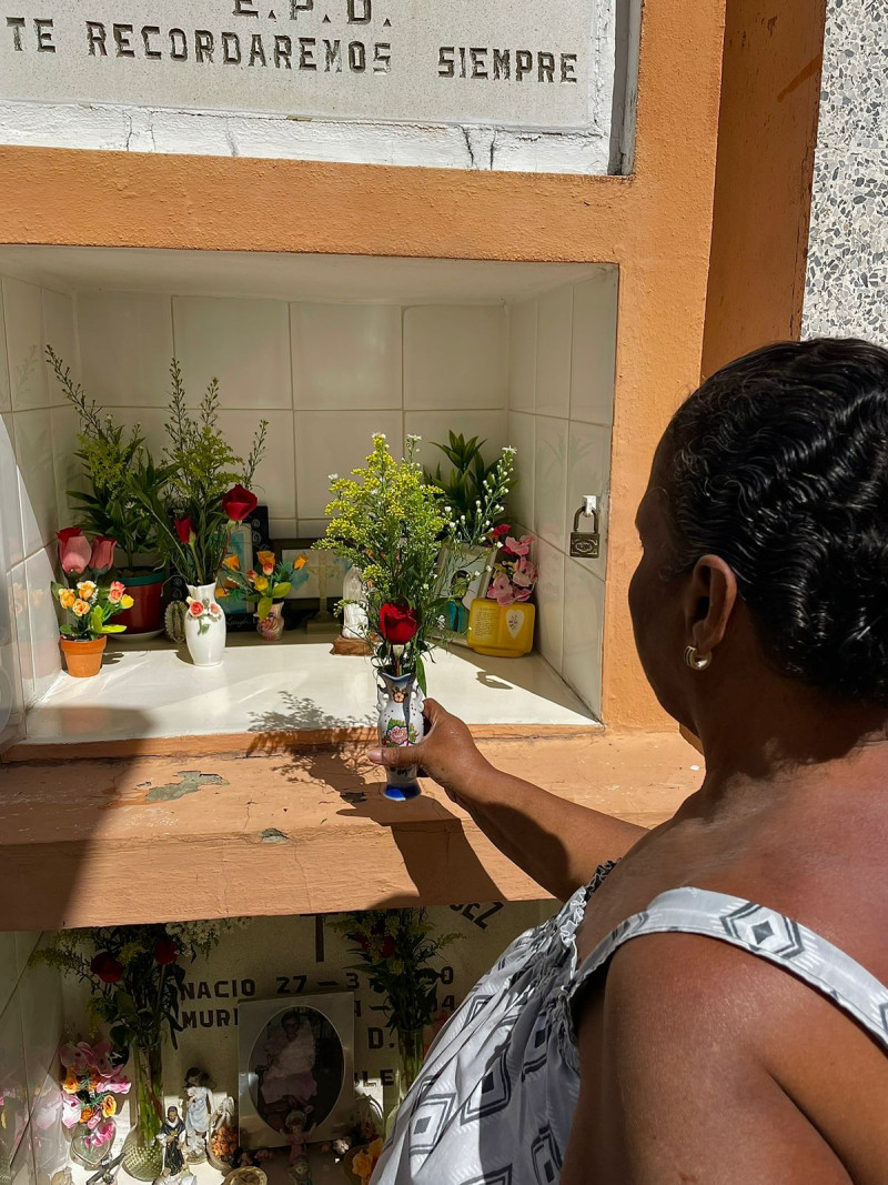 Carmen Rodríguez de 72 años, coloca ofrendas en la tumba de su madre, quien falleció hace casi tres décadas