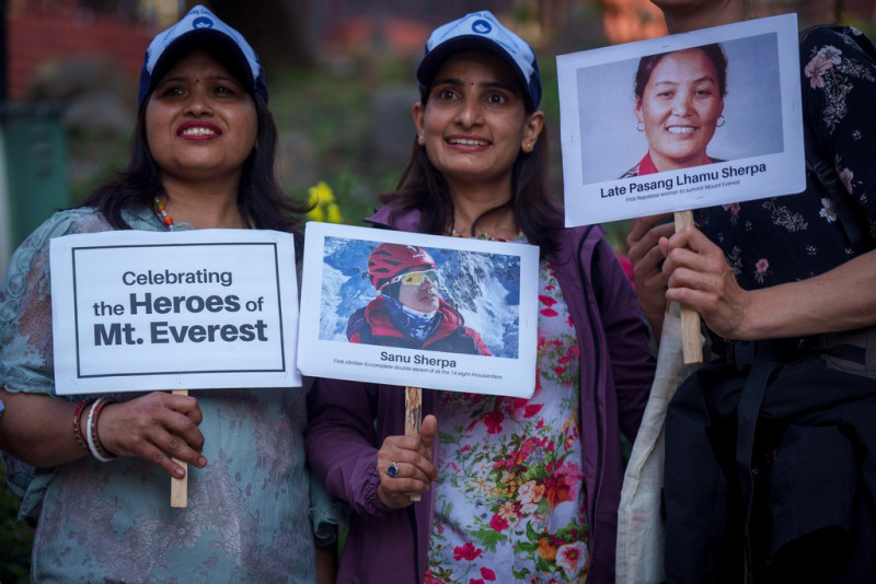 Tres mujeres sostienen carteles y fotos en homenaje a montañeros con récords, en los actos por el 70mo aniversario del primer ascenso a la cima del Everest en Katmandú, Nepal.