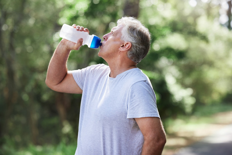 Hombre bebiendo agua por el calor. Asegúrese de obtener la hidratación adecuada durante sus entrenamientos.