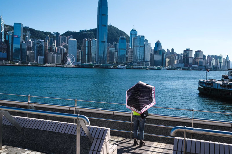 Una mujer que lleva un paraguas se encuentra bajo el sol durante la ola de calor en Hong Kong.