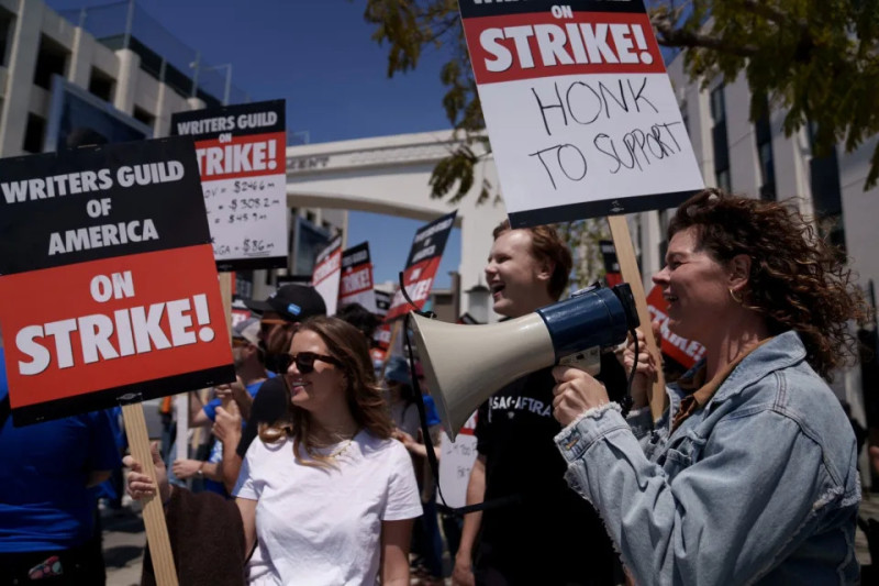 Los miembros del Gremio de Escritores en huelga sostienen carteles durante un mitin frente al estudio de Paramount Pictures, el miércoles 17 de mayo de 2023, en Los Ángeles.