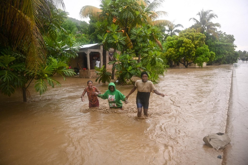 Residentes cruzan la Ruta Nacional 2 sumergida en L'Acul en el Arrondissement de Léogâne a 37 km al oeste de Puerto Príncipe, Haití, el 3 de junio de 2023, durante las fuertes lluvias.