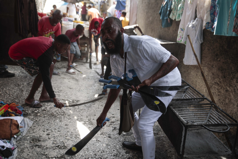 Nertil Marcelin, líder de un grupo comunitario, y miembros de la comunidad golpean machetes contra el suelo el domingo 28 de mayo de 2023, en respaldo al movimiento "Bwa Kale", una iniciativa para combatir a pandillas que intentan controlar su vecindario en el distrito Delmas de Puerto Príncipe, Haití.