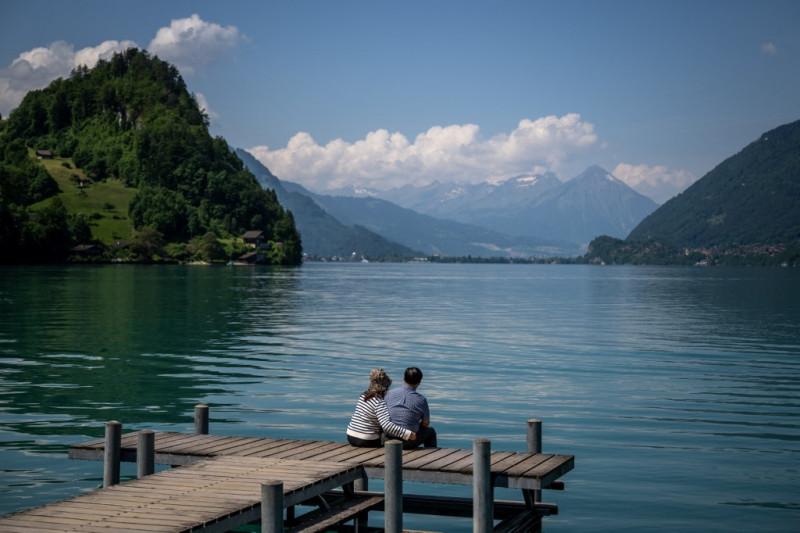 Un par de turistas se sientan en el famoso muelle de una serie de Netflix de Corea del Sur en el pueblo de Iseltwald a orillas del lago Brienz, en los Alpes suizos, el 2 de junio de 2023.