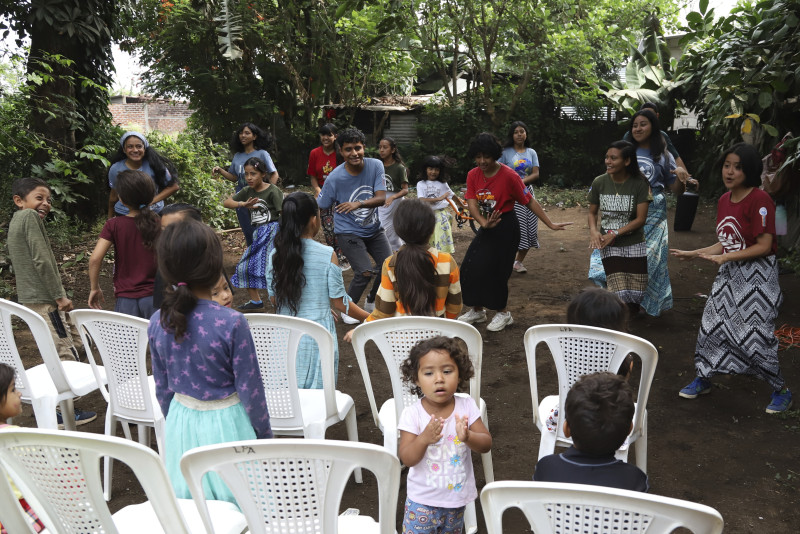 Miembros de la Iglesia Asambleas de Dios lanzan oraciones y bailan durante un día de enseñanza de la Biblia para niños, en una comunidad antes bajo el control de las pandillas, en Santa Ana, El Salvador, el sábado 29 de abril de 2023.