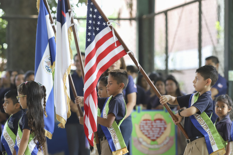 Niños salvadoreños portan las banderas nacionales de Estados Unidos y El Salvador en una ceremonia de bienvenida a un grupo de donantes estadounidenses, en la escuela Hosanna, una institución manejada por la Iglesia Asambleas de Dios, en una zona antes controlada por las pandillas, en Santa Ana, El Salvador, el sábado 29 de abril de 2023.