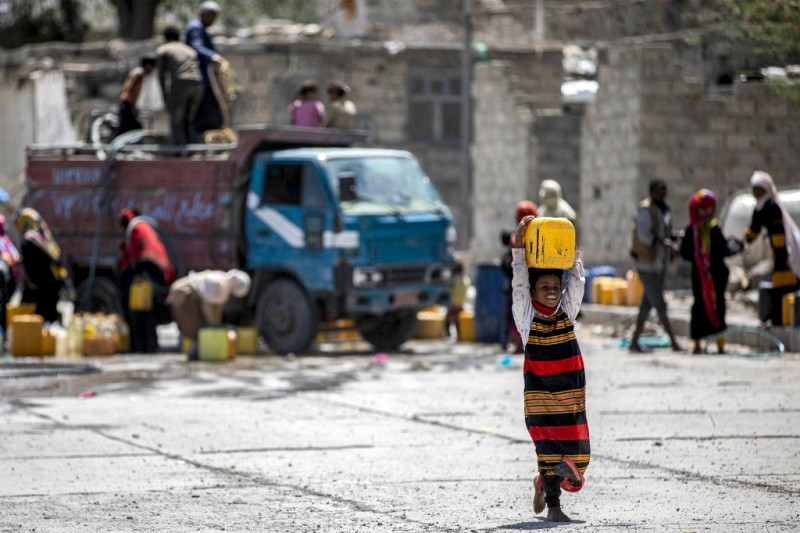 En esta imagen tomada el 8 de junio de 2023, una niña camina con un bidón lleno de agua de un camión cisterna en las afueras de Taez, la tercera ciudad de Yemen.