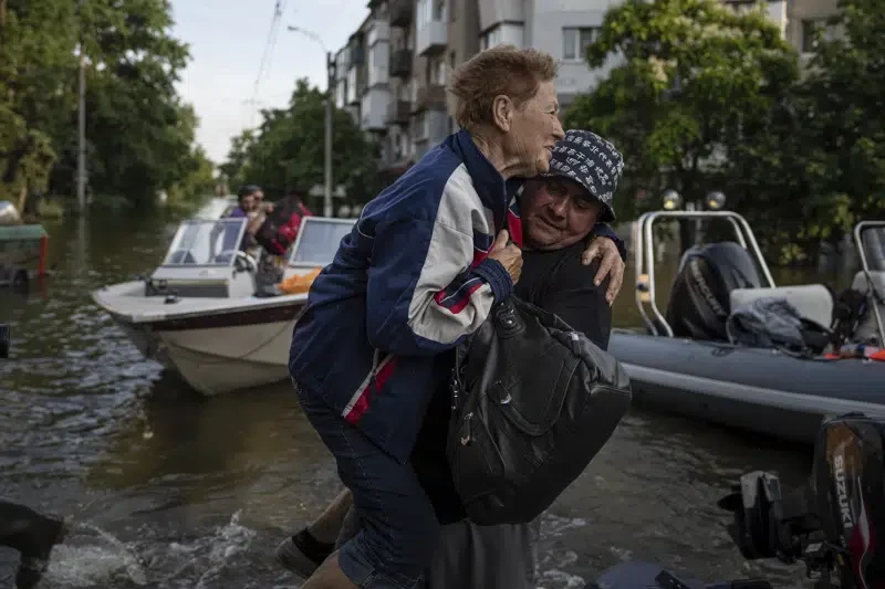 Un voluntario lleva en brazos a una mujer durante su evacuación desde la anegada localidad de Kardashynka, en la orilla izquierda del río Dniéper, en Jersón, Ucrania, el 9 de junio de 2023.