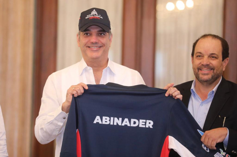 El presidente Luis Abinader recibe la chaqueta con su apellido y la gorra oficial de la delegación dominicana.
