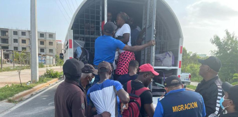 Haitianos son subidos a camioneta por agentes de control migratorio.
