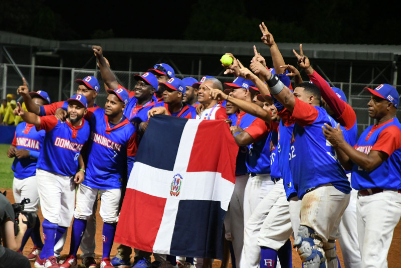 El equipo de República Dominicana de softbol celebra en el estadio Pablo Arnoldo Guzmán con la bandera tricolor tras obtener la medalla de oro.