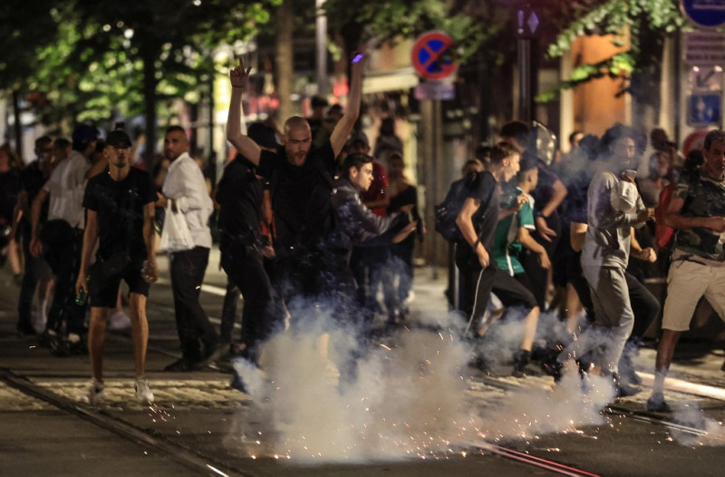 Los manifestantes huyen de una explosión de fuegos artificiales en una calle de Niza, sureste de Francia, a principios del 2 de julio de 2023, durante la quinta noche de disturbios tras el tiroteo de un conductor. adolescente en el suburbio parisino de Nanterre el 27 de junio