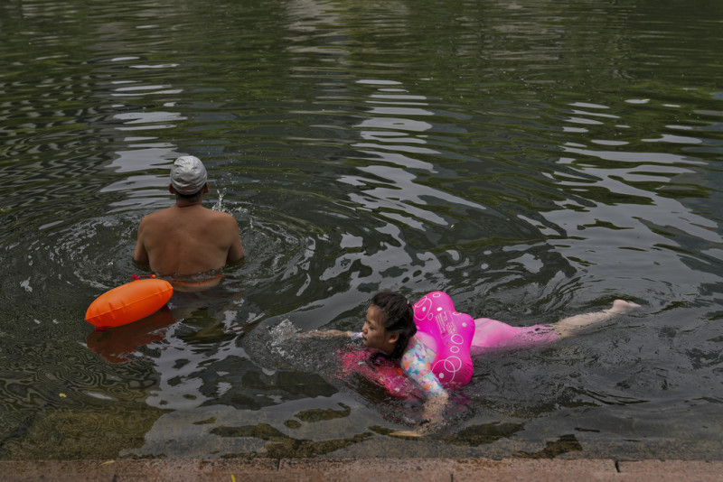 Vecinos nadando en un canal urbano para refrescarse en un día inusualmente caluroso en Beijing, el lunes 3 de julio de 2023.