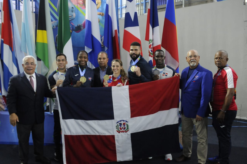 Ejecutivos, entrenadores y atletas de karate celebran su éxito con la bandera nacional.