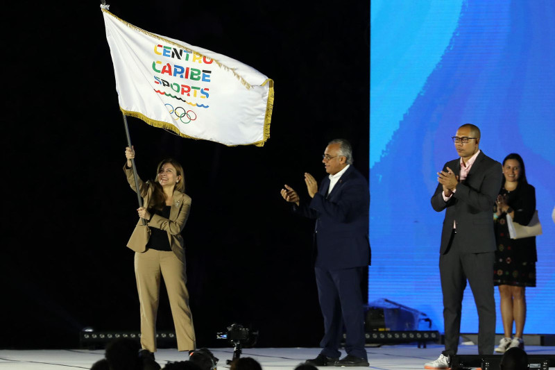 La alcaldesa Carolina Mejía ondea la bandera de Centro Caribe Sports en la ceremonia de clausura.