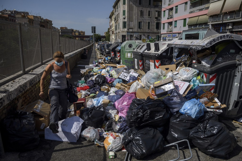 Un residente pasa junto a contenedores de basura desbordados en las calles, mientras la ciudad lucha con un problema de basura agravado por el calor del verano, el 7 de julio de 2021 en Roma, Italia.
