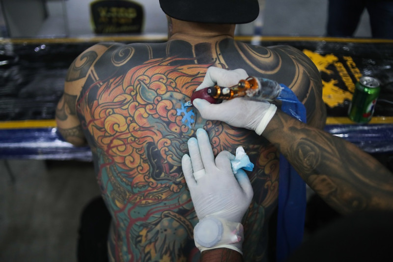 Un tatuador trabaja sobre la piel de un hombre. El 17 de julio se celebra el Día Internacional del tatuaje.