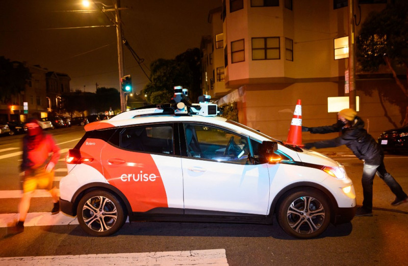 Miembros de SafeStreetRebel, un grupo de activistas anónimos contra los coches, colocan un cono en un robotaxi autoconducido para inutilizarlo en San Francisco, California, el 11 de julio de 2023