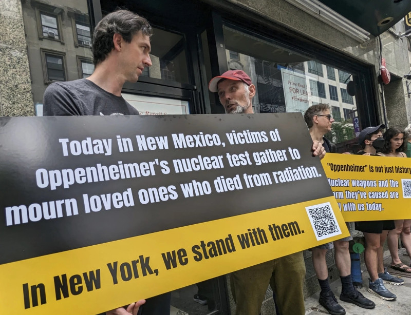Matthew Bolton, a la izquierda, y Jan-Christoph Zoels, al centro, sostienen un cartel mientras se manifiestan en la ciudad de Nueva York el 15 de julio de 2023.