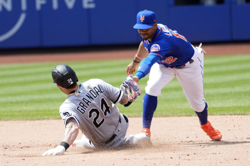Yasmani Grandal de los Medias Blancas de Chicago se desliza en la segunda base ante el torpedero Francisco Lindor de los Mets de Nueva York.