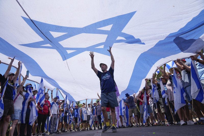 Los manifestantes ondean una gran bandera israelí