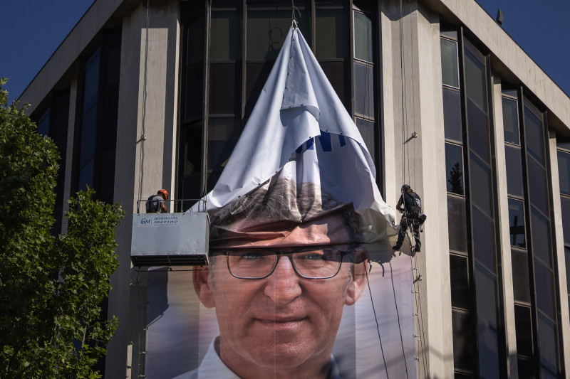 Trabajadores retiran un cartel electoral que muestra a Alberto Feijóo, líder del conservador Partido Popular, en la sede del partido en Madrid, ayer.