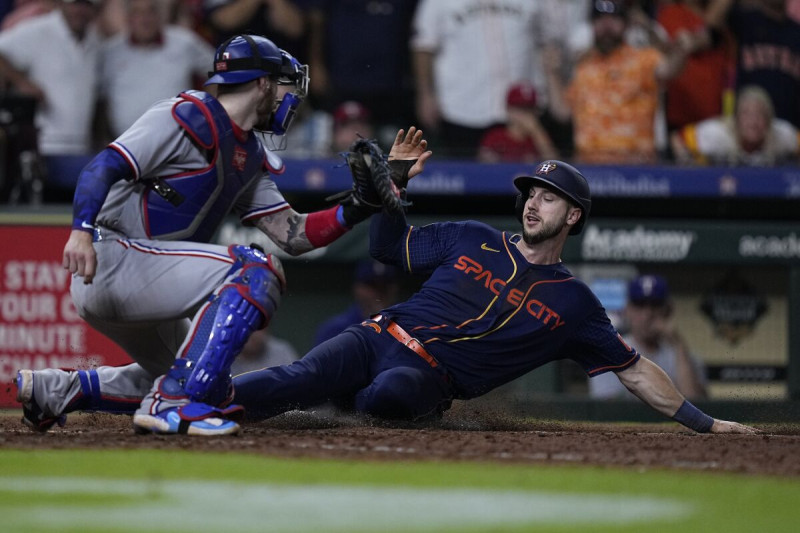 Kyle Tucker de los Astros anota la carrera de la victoria superando al catcher de los Rangers Jonah Heim tras el sencillo del dominicano Yainer Díaz.