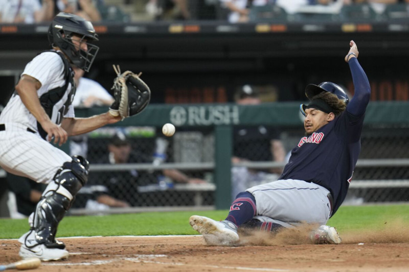 Josh Naylor, de los Guardianes de Cleveland, se desliza para anotar frente al cátcher mexicano Seby Zavala, de los Medias Blancas de Chicago.