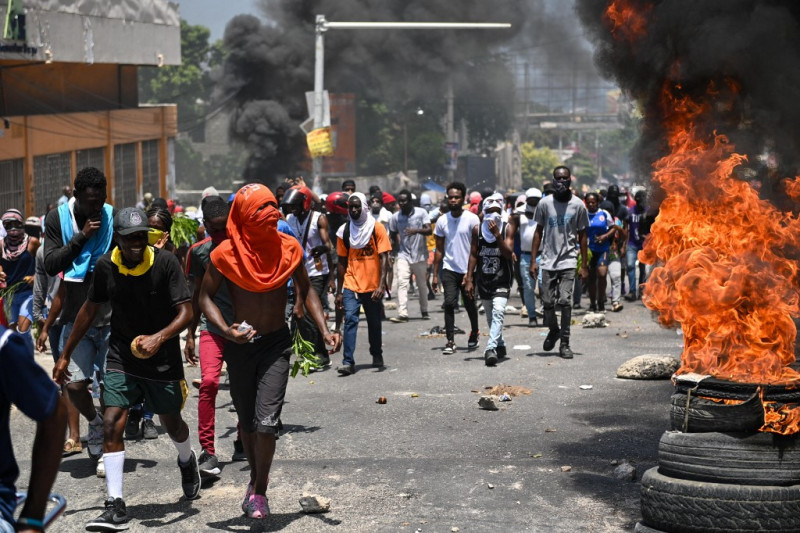 La gente marcha mientras se queman los neumáticos durante una protesta contra la inseguridad, el 7 de agosto de 2023, cerca de la casa oficial del Primer Ministro en Puerto Príncipe, Haití.